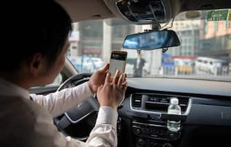 In this picture taken on October 18, 2018, a driver working for ride-sharing company Didi uses his smartphone to choose the best driving route to bring a customer to his destination in Beijing. - Didi is a popular taxi and ride-sharing service in China that is operated via a smartphone app. (Photo by Nicolas ASFOURI / AFP)        (Photo credit should read NICOLAS ASFOURI/AFP via Getty Images)