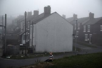 A little boy sits in front of the pit houses which were once full of families supported by the coal mine. The houses were mostly bought by the miners with a payoff when they were made redundant from the closures, but the houses are now almost completely valueless as there is so little work and most are boarded up.