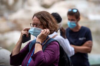 ROME, ITALY - OCTOBER 02: People wearing protective masks walk around the Fontana di Trevi (Trevi Fountain) amid Covid-19 pandemic, on October 02, 2020 in Rome, Italy. The Lazio region President Nicola Zingaretti set an order obliging people to wear face masks in public including outdoors due to the increase of Covid-19 cases in the Lazio region. (Photo by Antonio Masiello/Getty Images)