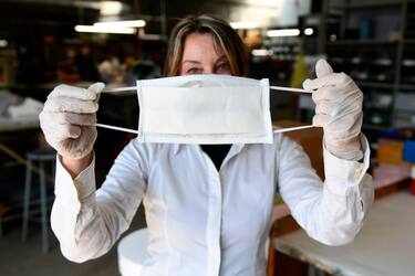 An employee shows a surgical masks at a leather workshop turned into a mask factory, close to Vigevano, Lombardy, on March 19, 2020 during the country's lockdown within the new coronavirus pandemic. - A crafts company specialized in the production of leather goods and accessories for the automotive and clothing sector, has now turned its activity to the production of surgical masks on behalf of a company from the nearby town of Galliate, in the wake of the needs following the coronavirus pandemic. (Photo by MIGUEL MEDINA / AFP) (Photo by MIGUEL MEDINA/AFP via Getty Images)