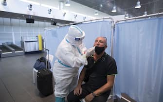CASELLE TORINESE, ITALY - AUGUST 26: Medical staff in full PPE using swabs test on man after a flight from Ibiza, Spain to Turin on August 26, 2020 in Turin, Italy. At Italian airports, all travelers from countries at risk of Covid-19 are tested with swabs to prevent the spread of Covid 19 in Italy. (Photo by Stefano Guidi/Getty Images)