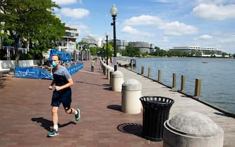 epa08446074 A runner wears a face mask while jogging at the waterfront in Georgetown, Washington, DC, USA, 26 May 2020. The nation's capital may begin lifting coronavirus COVID-19 restrictions as early as 29 May, according to Mayor of Washington, DC, Muriel Bowser. Bowser is expected to make an announcement on 27 May regarding reopening, which could occur if the current data trend continues.  EPA/MICHAEL REYNOLDS