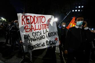Un manifestante con uno striscione durante la protesta per il reddito universale 'Tu ci chiudi tu ci paghi', Roma, 31 ottobre 2020. ANSA/RICCARDO ANTIMIANI