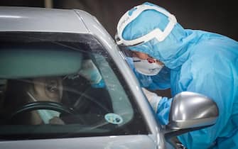 Tampone drive through: un'operatrice sanitaria esegue il test su una donna in macchina