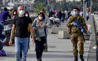 Un militare controlla i passanti invitandoli ad indossare la mascherina sul lungomare di Napoli a poche ore dall' applicazione dei limiti di circolazione per l'inserimento della Campania nelle area  di ' Zona Rossa'   14 novembre  2020ANSA / CIRO FUSCO