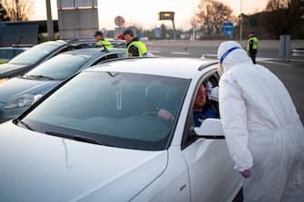 A medical worker measures the body temperature of a motorist as police check documents at the  Slovenian-Italian border crossing near Nova Gorica, on March 11, 2020, after Slovenia's government announced it would close its border with Italy, hard hit by the outbreak of COVID-19, the new coronavirus. - Italy's neighbours Austria and Slovenia announced on March 10 Tuesday strict travel restrictions and other measures in the wake of similar moves by Rome to limit the spread of the new coronavirus. (Photo by Jure Makovec / AFP) (Photo by JURE MAKOVEC/AFP via Getty Images)