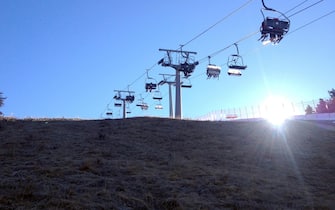 Una seggiovia in funzione sopra i prati che circondano la pista Stelvio di Bormio dove è possibile sciare solo grazie all'innevamento artificiale,  1 gennaio 2016.
ANSA / MATTEO BAZZI
