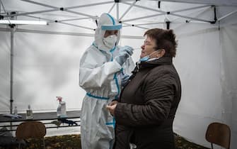 epa08788104 An Austrian Military medic collects a swab sample from a person at a coronavirus disease testing site during a nationwide testing in Bratislava, Slovakia, 31 October 2020. A total of 50 Austrian military medics help Slovakia with the mass testing.  EPA/JAKUB GAVLAK