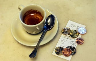 Caffè, monete e scontrino fiscale sul bancone di un bar