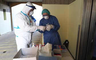 Health workers wearing overalls and protective masks shows a swab performed on motorist seated in his car in Bologna, Italy, 18 March 2020. One swab every five minutes, 12. This is the rhythm guaranteed by the new way of performing the coronavirus positivity test, experimented in Bologna today at San Lazzaro di Savena. It is called 'drive-thru buffer' and takes over what has already been successfully tested in South Korea and Australia. It provides the test directly on board on one's car, in a safer and faster way. ANSA/ GIORGIO BENVENUTI