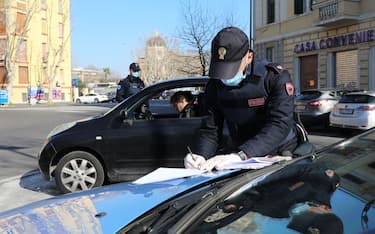 ROME, ITALY - MARCH 15: A Police patrol of the Ostia Commissariat checks if the occupants of a car are respecting the quarantine on March 15, 2020 in Rome, Italy. Ostias streets, one of Rome neighborhood were eerily quiet on the forth day of a nationwide quarantine. The Italian Government has taken the unprecedented measure of a nationwide lockdown by closing all businesses except essential services such as, pharmacies, grocery stores, hardware stores, tobacconists and banks, in an effort to fight the world's second-most deadly Coronavirus (COVID-19) outbreak outside of China.The movements in the streets are allowed only for work reasons and health reasons proven by a medical certificate. Citizens are encourage to stay home and have an obligation to respect the safety distance of one meter from each other in a row at supermarkets or in public spaces. According to the Ministry of the Interior, of the over half a million people controlled by the police in the past four days, over 20 thousand people have been reported for violating the quarantine. (Photo by Marco Di Lauro/Getty Images)