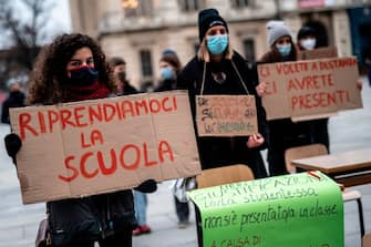 A student holds a sign reading " let's get back the school "  as they demonstrate against the Italian Government's decision to continue the closure of high schools to stem the spread of the Covid-19 pandemic, caused by the novel coronavirus in Piazza Castello in Turin on January 7, 2021. (Photo by Marco Bertorello / AFP) (Photo by MARCO BERTORELLO/AFP via Getty Images)