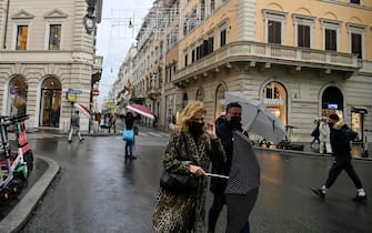 Alcune persone in giro per i negozi di via del Corso nel centro di Roma, approfittando del ritorno della "zona arancione" nonostante la pioggia a Roma, 28 dicembre 2020. ANSA/RICCARDO ANTIMIANI