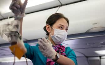 epa08185837 A flight attendant of Cambodian Lanmei Airlines demonstrates safety procedures in the airplane while wearing a face mask during a flight from Sihanoukville, Cambodia, via Phnom Penh, Cambodia to Guangzhou, Guangdong Province, China, 01 February 2020. Guangzhou Airport usually busy during the end of Spring Festival when Chinese travelers return to their homes, appears deserted after many countries and international airlines are suspending or limiting flights routes to China, including American Airlines, British Airways, and Lufthansa, because of outbreak of Coronavirus in Wuhan City, Hubei Province. Rare passengers who were able to board airplanes to China, are required to fill health declaration forms explaining if they were in Hubei Province in last 14 days and their body temperature is monitored several times on the terminal.  EPA/Alex Plavevski