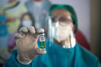 TOPSHOT - A health worker holds up a vial of Covishield, AstraZeneca-Oxford's Covid-19 coronavirus vaccine, at the Ayeyarwady Covid Center in Yangon on January 27, 2021. (Photo by Sai Aung Main / AFP) (Photo by SAI AUNG MAIN/AFP via Getty Images)