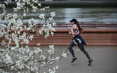 LONDON, ENGLAND - MARCH 28: A woman jogs past a flowering tree in Battersea Park on March 28, 2021 in London, England. Starting tomorrow, England will ease its rules on socialising and recreation, with groups of either six people or two households allowed to meet outdoors. Outdoor organised sports will also be allowed to resume. Covid-19 cases have dropped steadily after months of lockdown measures and progressing vaccination campaign. (Photo by Hollie Adams/Getty Images)