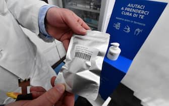 Un farmacista con una confezione che custodisce una dose di vaccino anti-Covid