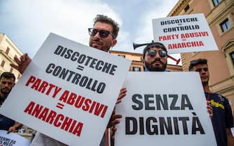 Cartelli di protesta mostrati alla manifestazione dei gestori delle discoteche in Piazza San Silvestro, a Roma, l'8 luglio 2021 