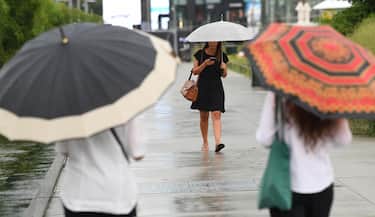 Persone camminano sotto la pioggiaa causa del maltempo a Milano, 26 luglio 2021. ANSA/DANIEL DAL ZENNARO