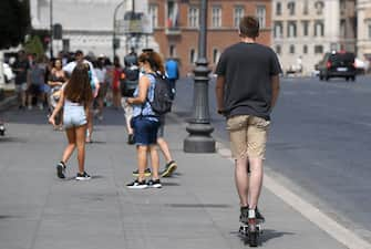 Un ragazzo guida un monopattino in via dei Fori Imperiali a Roma, 11 agosto 2021.  ANSA/ETTORE FERRARI
 