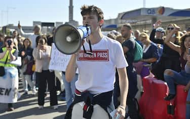 GENOA, ITALY - OCTOBER 15: No Green Pass protester holds a megaphone during the protest in front of Genoa Port on October 15, 2021 in Genoa, Italy. As of October 15, the 23 million civil servants and employees in Italy must present proof of vaccination or a negative Covid-19 test to work. A measure that could paralyze certain sectors of the economy. (Photo by Stefano Guidi/Getty Images)
