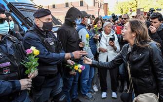 Women hand flowers to police officers during a protest against the so-called Green Pass on October 15, 2021 at Circo Massimo in Rome, as new coronavirus restrictions for workers come into effect. - Italy braced for nationwide protests, blockades and potential disruption on October 15, 2021 as all workers must show a so-called Green Pass, offering proof of vaccination, recent recovery from Covid-19 or a negative test, or face being declared absent without pay. (Photo by Alberto PIZZOLI / AFP) (Photo by ALBERTO PIZZOLI/AFP via Getty Images)