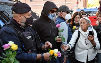 A woman hands a flower to a police officer during a protest against the so-called Green Pass on October 15, 2021 at Circo Massimo in Rome, as new coronavirus restrictions for workers come into effect. - Italy braced for nationwide protests, blockades and potential disruption on October 15, 2021 as all workers must show a so-called Green Pass, offering proof of vaccination, recent recovery from Covid-19 or a negative test, or face being declared absent without pay. (Photo by Alberto PIZZOLI / AFP) (Photo by ALBERTO PIZZOLI/AFP via Getty Images)