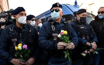 Police officers hold flowers handed to them by women during a protest against the so-called Green Pass on October 15, 2021 at Circo Massimo in Rome, as new coronavirus restrictions for workers come into effect. - Italy braced for nationwide protests, blockades and potential disruption on October 15, 2021 as all workers must show a so-called Green Pass, offering proof of vaccination, recent recovery from Covid-19 or a negative test, or face being declared absent without pay. (Photo by Alberto PIZZOLI / AFP) (Photo by ALBERTO PIZZOLI/AFP via Getty Images)