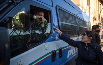 1235897432 ROME, ITALY - OCTOBER 15: A woman hands flowers to Police officers during a demonstration organized by No Green Pass, No Vax and far-right movements against the Green Pass, following the new decree outlined by Italian Government, at Circo Massimo, on October 15, 2021 in Rome, Italy. As of October 15, the 23 million civil servants and employees in Italy must present proof of vaccination or a negative Covid-19 test to work. A measure that could paralyze certain sectors of the economy. (Photo by Antonio Masiello/Getty Images)