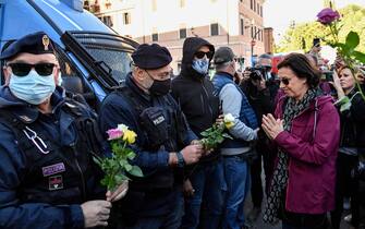 A woman gestures after she handed flowers to police officers during a protest against the so-called Green Pass on October 15, 2021 at Circo Massimo in Rome, as new coronavirus restrictions for workers come into effect. - Italy braced for nationwide protests, blockades and potential disruption on October 15, 2021 as all workers must show a so-called Green Pass, offering proof of vaccination, recent recovery from Covid-19 or a negative test, or face being declared absent without pay. (Photo by Alberto PIZZOLI / AFP) (Photo by ALBERTO PIZZOLI/AFP via Getty Images)