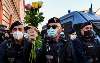 A police officer holds flowers handed to him by women during a protest against the so-called Green Pass on October 15, 2021 at Circo Massimo in Rome, as new coronavirus restrictions for workers come into effect. - Italy braced for nationwide protests, blockades and potential disruption on October 15, 2021 as all workers must show a so-called Green Pass, offering proof of vaccination, recent recovery from Covid-19 or a negative test, or face being declared absent without pay. (Photo by Alberto PIZZOLI / AFP) (Photo by ALBERTO PIZZOLI/AFP via Getty Images)