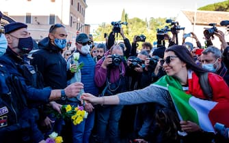 ROME, ITALY - OCTOBER 15: A woman gives flowers to Police officers during a demonstration organized by No Green Pass, No Vax and far-right movements against the Green Pass, following the new decree outlined by Italian Government, at Circo Massimo, on October 15, 2021 in Rome, Italy. As of October 15, the 23 million civil servants and employees in Italy must present proof of vaccination or a negative Covid-19 test to work. A measure that could paralyze certain sectors of the economy. (Photo by Stefano Montesi - Corbis/Corbis via Getty Images)
