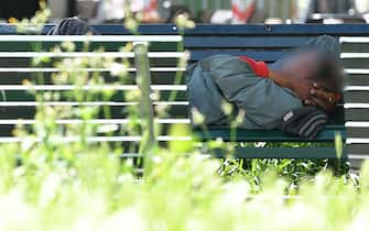 Un uomo dorme su una panchina a Milano