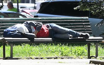 Un uomo dorme su una panchina a Milano