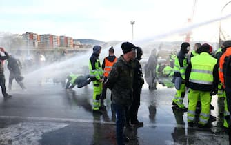 The police intervene with fire hydrants to disperse the dockers blocking gate 4 while demonstrating against the Green Pass in the port of Trieste, in northern Italy, October 18, 2021.
ANSA/PAOLO GIOVANNINI