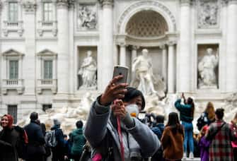A tourist wearing a respiratory mask takes a selfie photo at the Trevi fountain in downtown Rome on January 31, 2020. - The Italian government declared a state of emergency on January 31 to fast-track efforts to prevent the spread of the deadly coronavirus strain after two cases were confirmed in Rome. (Photo by Filippo MONTEFORTE / AFP) (Photo by FILIPPO MONTEFORTE/AFP via Getty Images)