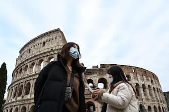TOPSHOT - Tourists wearing protective respiratory masks tour outside the Colosseo monument (Colisee, Coliseum) in downtown Rome on January 31, 2020. - The Italian government declared a state of emergency on January 31 to fast-track efforts to prevent the spread of the deadly coronavirus strain after two cases were confirmed in Rome. (Photo by Alberto PIZZOLI / AFP) (Photo by ALBERTO PIZZOLI/AFP via Getty Images)