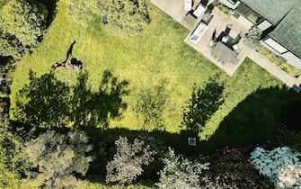 Aerial view of man cutting grass in backyard of home