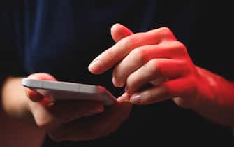 Mobile phone in the hands of a girl. A young woman in a black t-shirt is holding a phone. An email fraudster sends a message. The work of a freelancer, businessman.