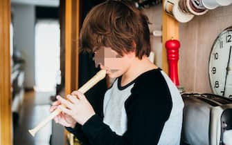 Close up of a boy playing the flute.