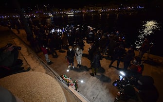 People stand by a memorial for the victims at the end of a torchlight procession of shipwreck survivors, relatives of victims, local residents and officials in the port of Giglio on January 13, 2022, marking the tenth anniversary of the January 13, 2012 Costa Concordia shipwreck off Giglio island, Tuscany, that killed 32. (Photo by Filippo MONTEFORTE / AFP) (Photo by FILIPPO MONTEFORTE/AFP via Getty Images)
