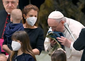 Pope Francis kisses a flag of Ukraine that comes from the city of Bucha as he meets Ukrainian children during the weekly general audience in Paolo VI Hall, Vatican City, 06 April 2022.  ANSA/ETTORE FERRARI 