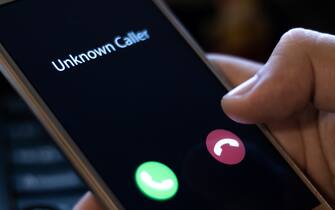 Unknown caller. A man holds a phone in his hand and thinks to end the call. Incoming from an unknown number at night. Incognito or anonymous
