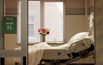 Vacant hospital bed in room with flowers and IV bag