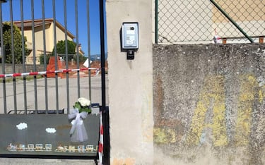 Un mazzo di fiori sul cancello chiuso della scuola dell'infanzia di Pile e dell'asilo Primo Maggio dove a seguito di un incidente ha perso la vita un bambino e sono rimaste ferite 5 persone, L'Aquila, 19 maggio 2022. 
ANSA/ FABIO IULIANO