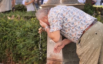 Uomo si rinfresca a una fontanella a Milano