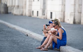 Una famiglia di turisti mangia un gelato seduta sul marciapiede di Piazza Navona cercando riparo dallÕondata di calore a Roma, 30 luglio 2020. MAURIZIO BRAMBATTI/ANSA