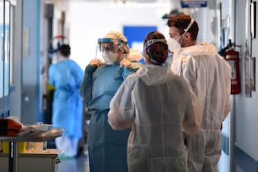 Medical staff members, wearing a personal protective equipment (PPE), gather in a corridor at a Covid-19 intensive care unit of Cremona hospital, in Cremona, northern Italy, on January 11, 2022. (Photo by Miguel MEDINA / AFP) (Photo by MIGUEL MEDINA/AFP via Getty Images)