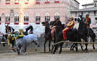 Italian jockey Stefano Piras (2ndL), who races for the "Bruco" district, falls during a false start of his horse "Uragano Rosso" (L) during the historical Italian horse race "Palio di Siena" on July 2, 2022 in Siena, Tuscany. (Photo by Alberto PIZZOLI / AFP) (Photo by ALBERTO PIZZOLI/AFP via Getty Images)