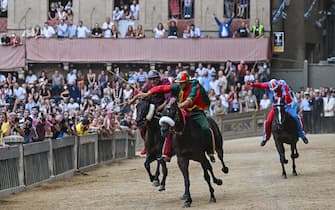 (From L) Italian jockey Jonatan Bartoletti riding Viso d'Angelo for the Torre ditrict, Italian jockey Giovanni Atzeni riding Zio Frac for the Drago district, and Italian jockey Elias Manucci riding Una per Tutti for the Pantera district, compete during the historical Italian horse race "Palio di Siena" on July 2, 2022 in Siena, Tuscany. (Photo by Alberto PIZZOLI / AFP) (Photo by ALBERTO PIZZOLI/AFP via Getty Images)